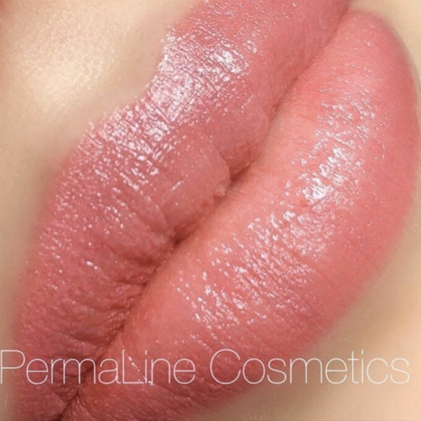 A close up of a pink lipstick on a woman's lips.