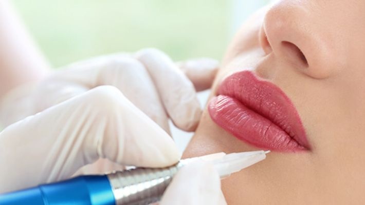 A woman is getting her lips injected with a needle.