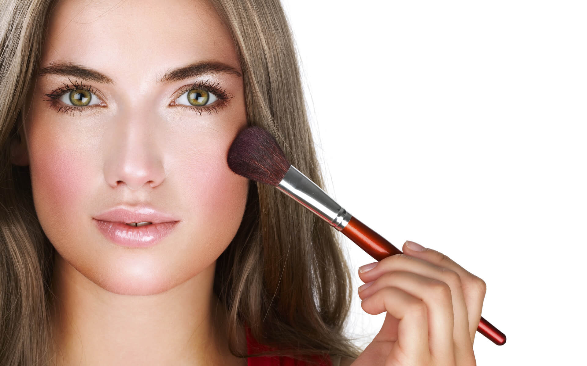 A woman using a brush to apply makeup to her face.
